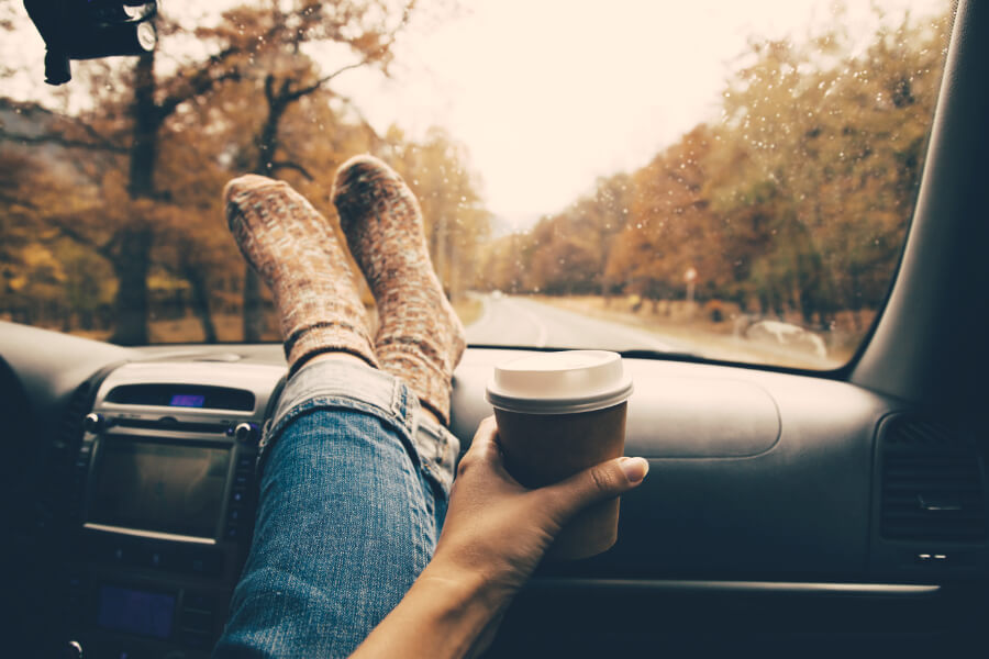 A woman stretching and enjoying coffee on her road trip