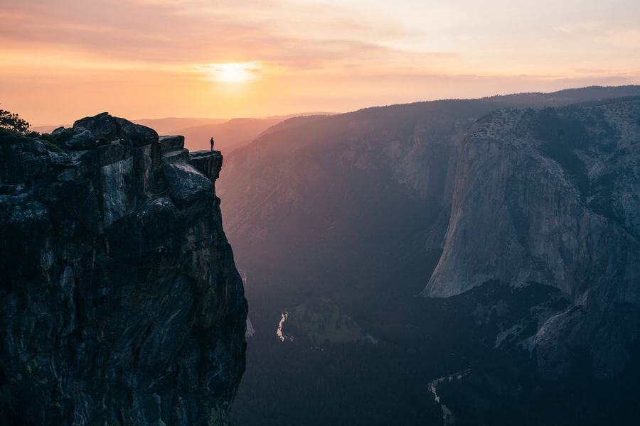 A hiker viewing a sunset in Yosemite National Park from Taft Point