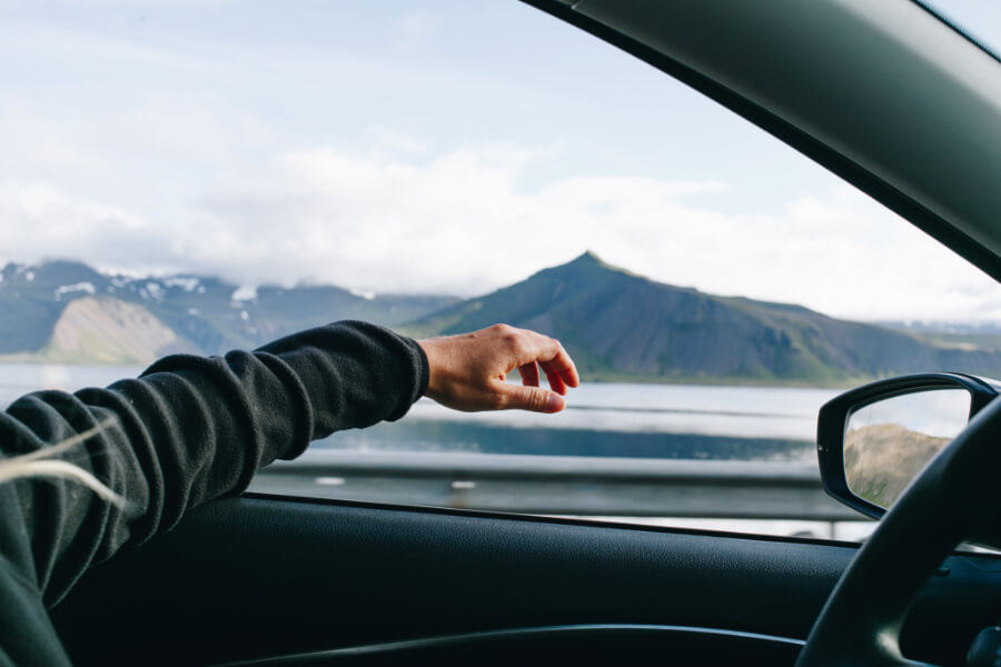A man with his hand out the window enjoying a road trip