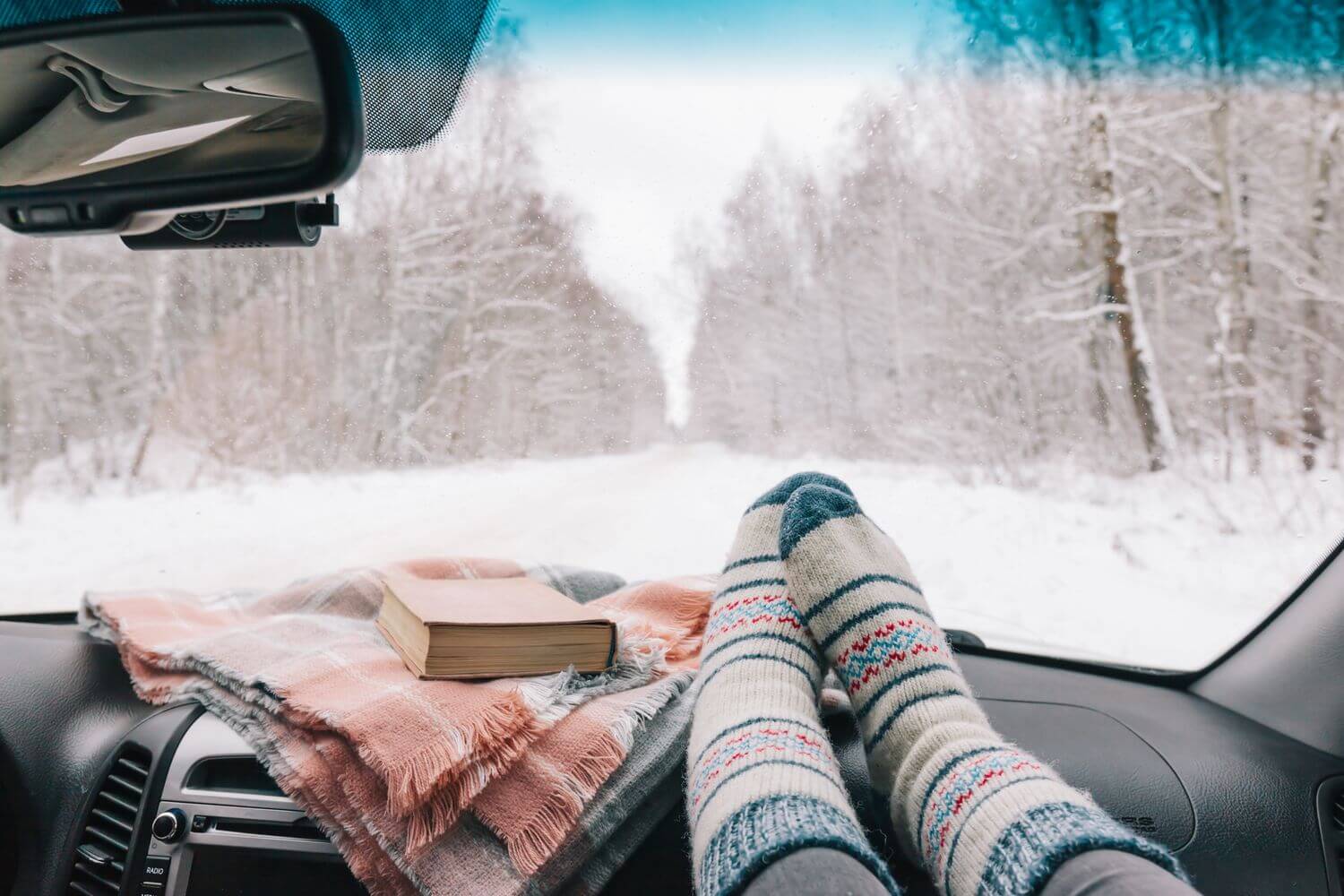 A woman with some road trip essentials in her car