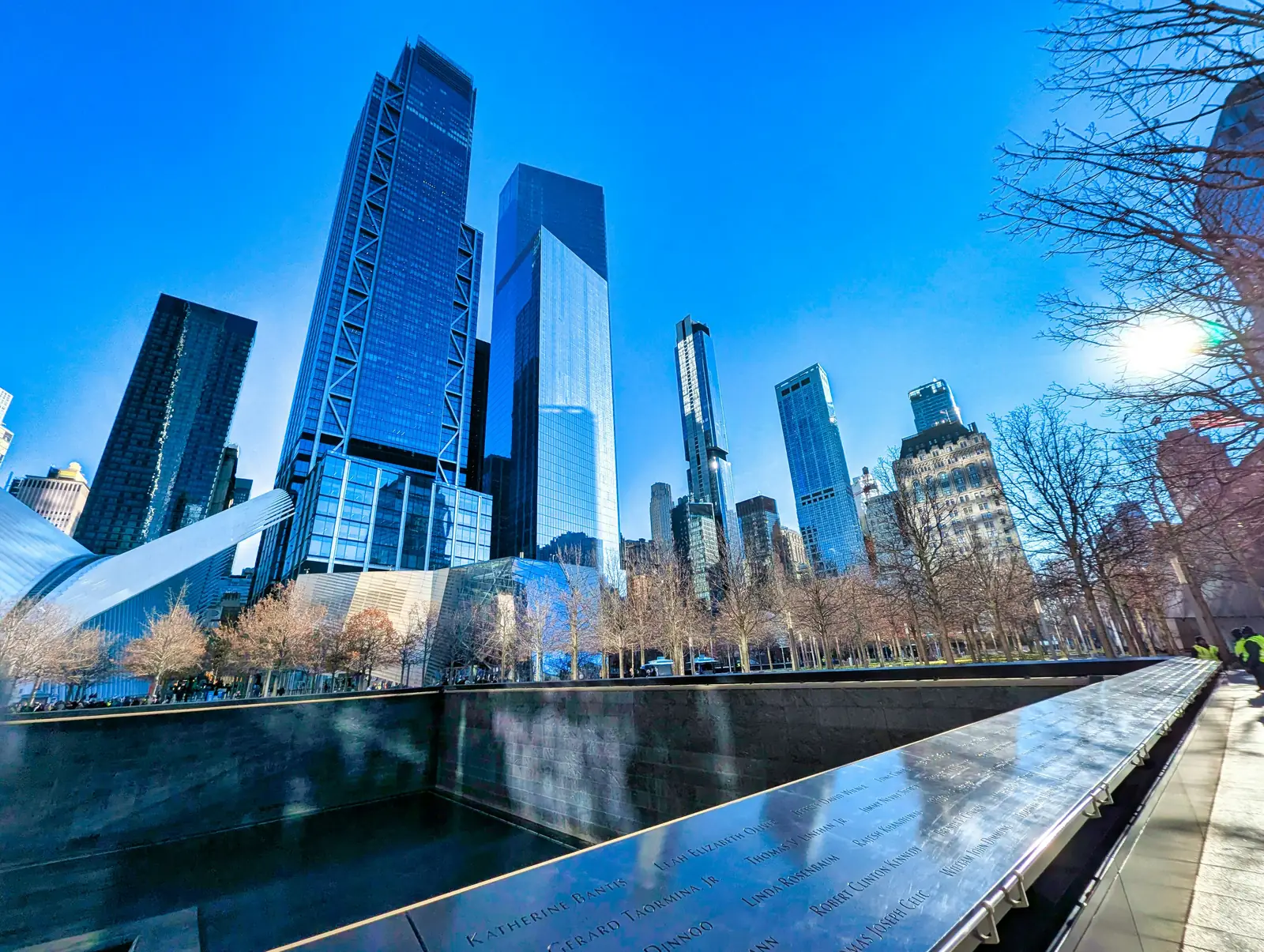 A reflecting pool at the 9/11 Memorial with skyscrapers rising behind it