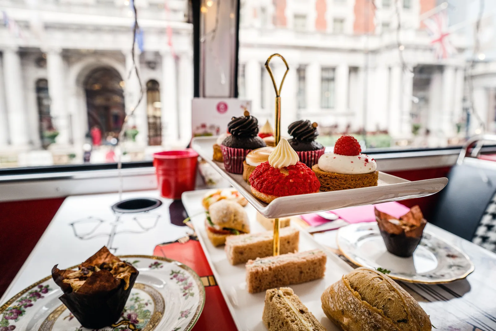 A tiered stand of cakes and sandwiches set for afternoon tea by a window