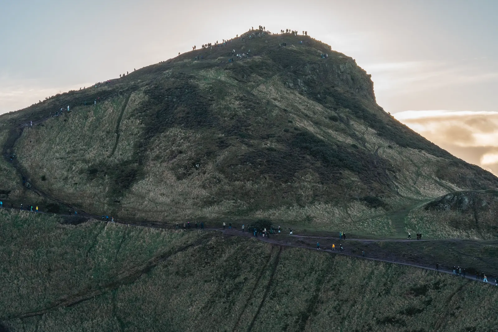 Walkers climbing the grassy peak of Arthur's Seat in Edinburgh