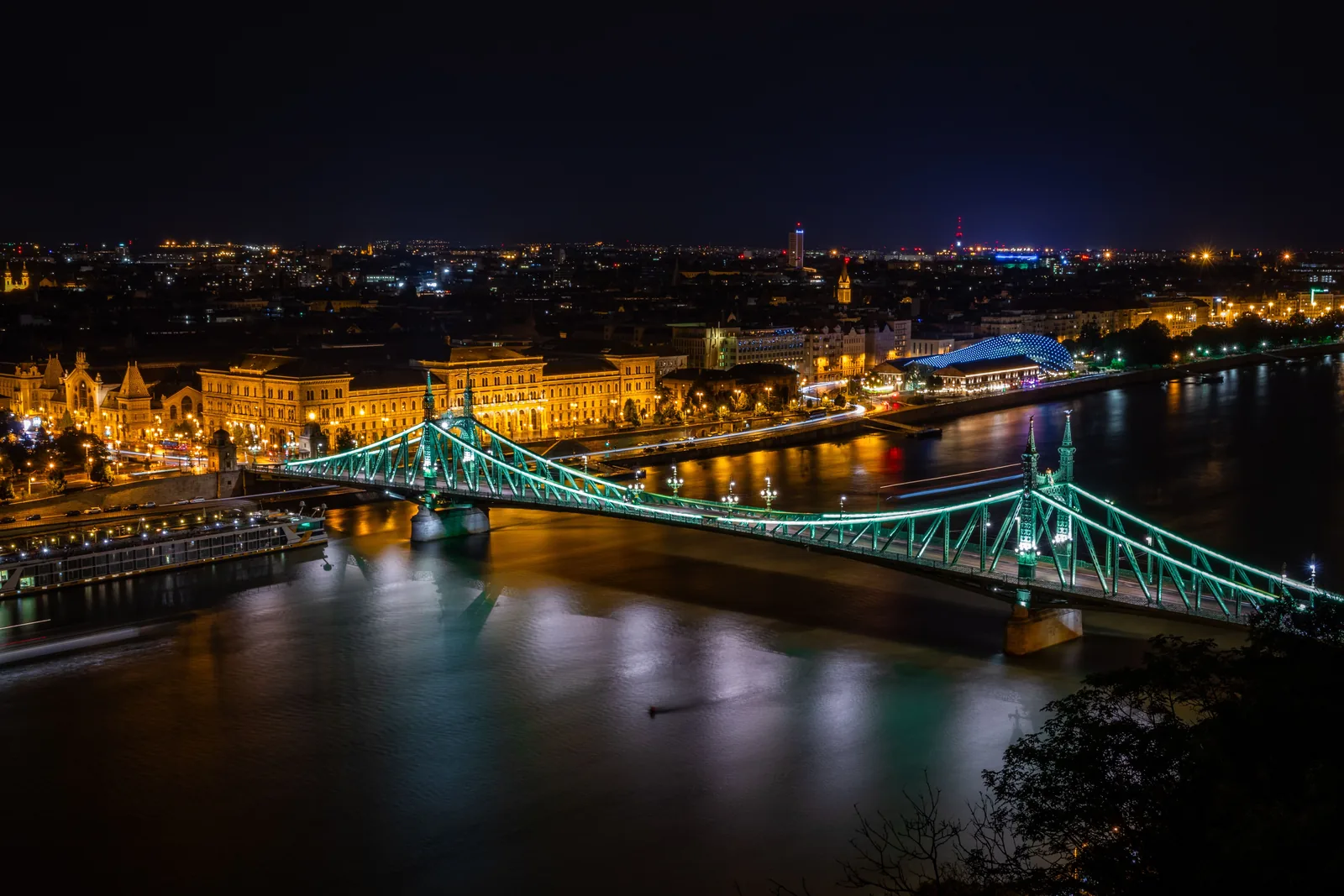 The Liberty Bridge and the Budapest skyline lit up at night over the Danube