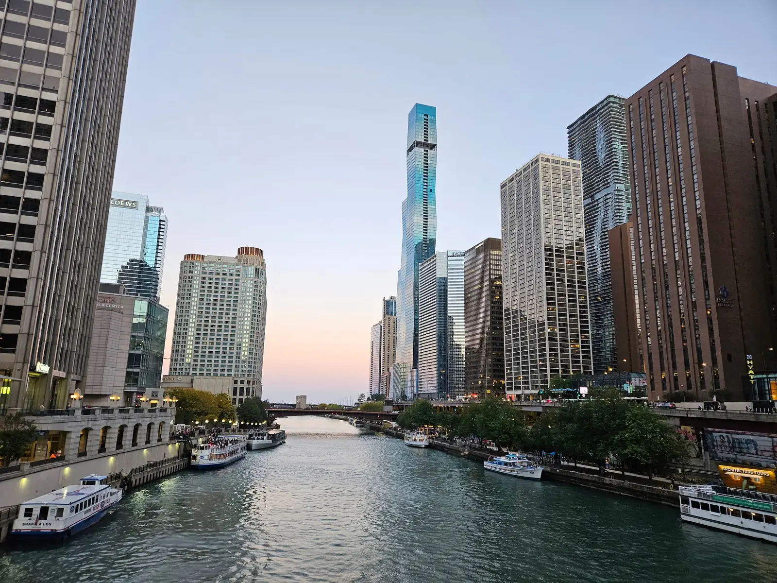 People walking along the Chicago Riverwalk beside downtown skyscrapers