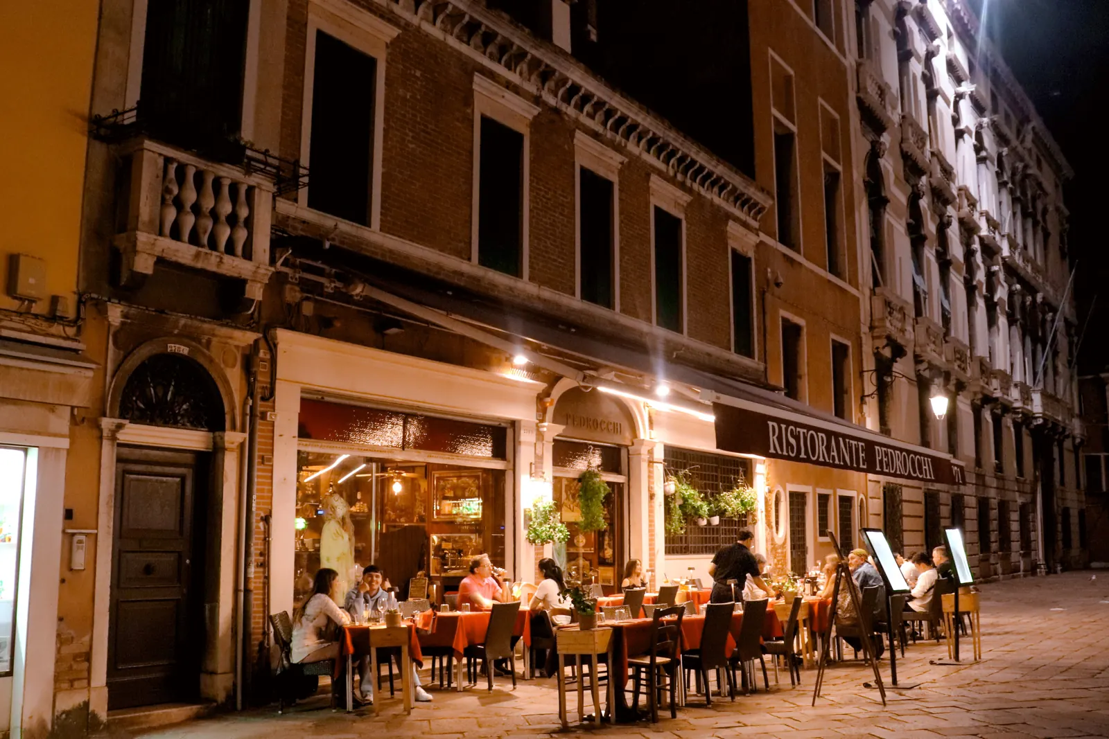 Diners at outdoor tables outside an Italian restaurant in the evening