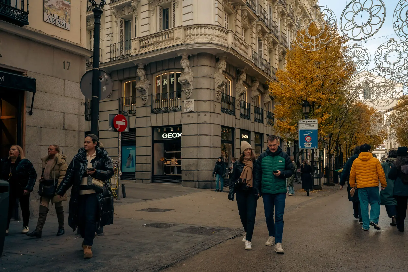 Shoppers in coats along a busy Madrid street in autumn