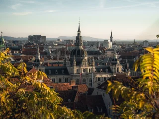 Golden evening light over the domes, spires, and red rooftops of Graz, Austria