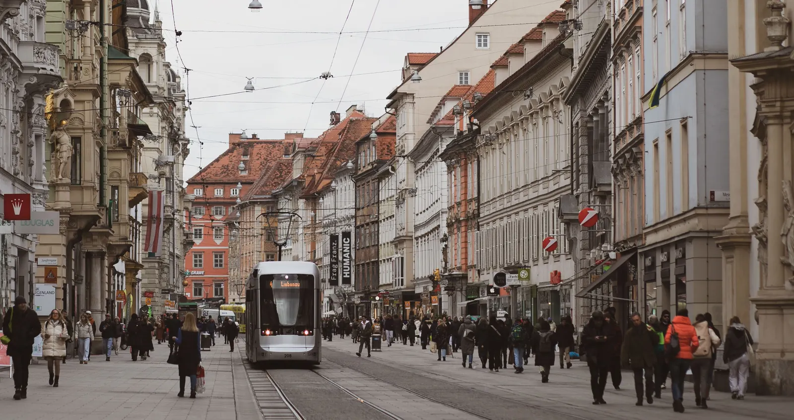 A tram running down Herrengasse in the old town of Graz between painted townhouses