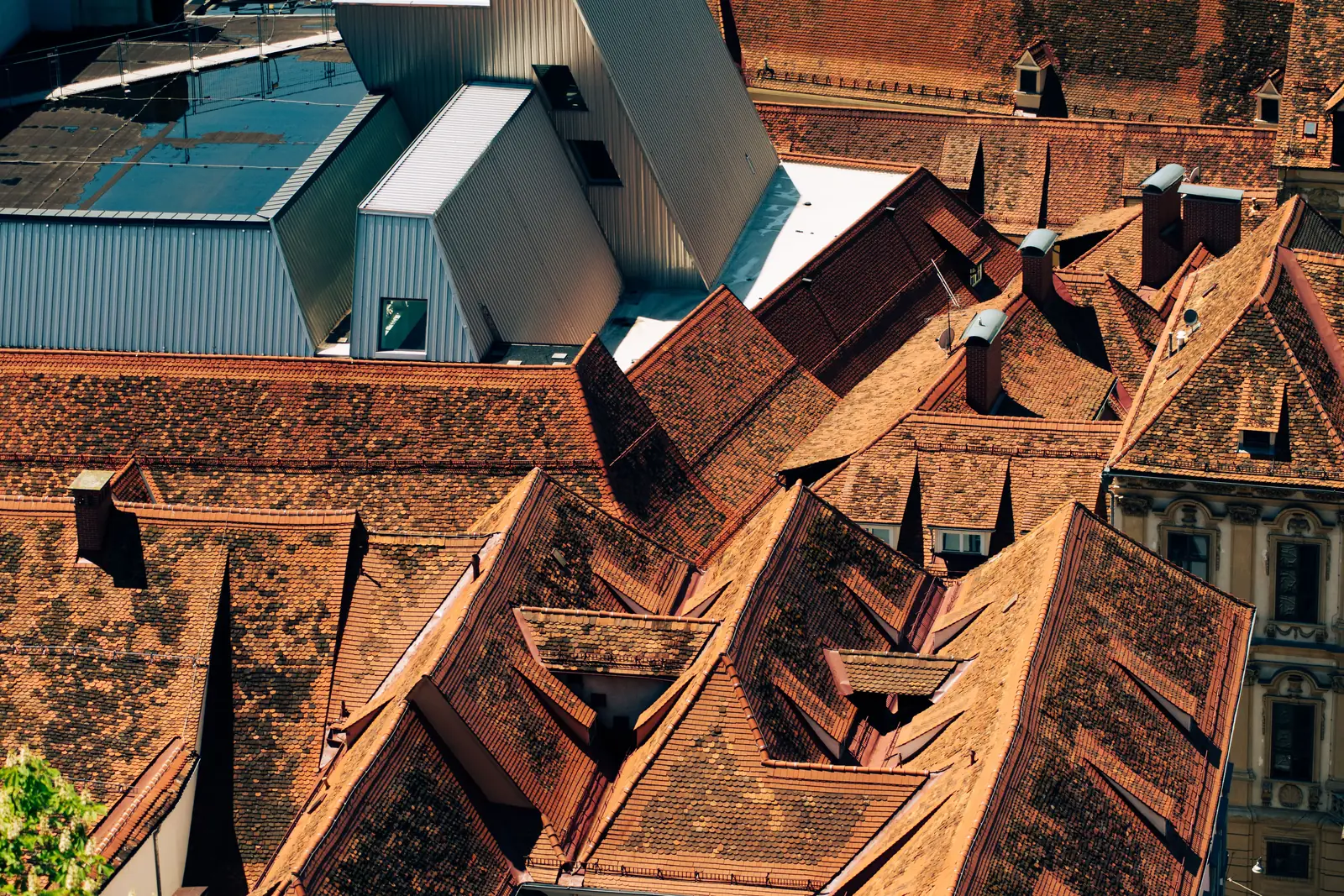 Layered orange and red clay tile rooftops in the old town of Graz in warm evening light