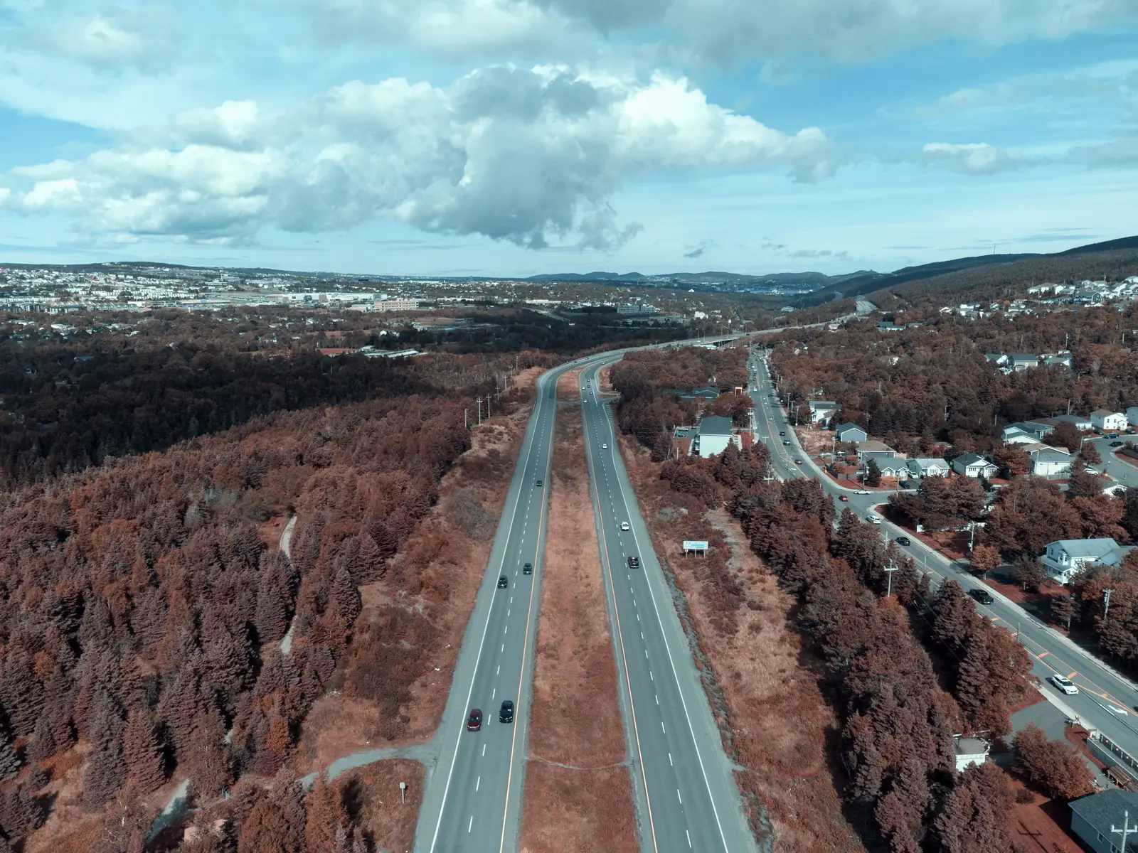 Aerial view of a highway with cars winding through autumn trees