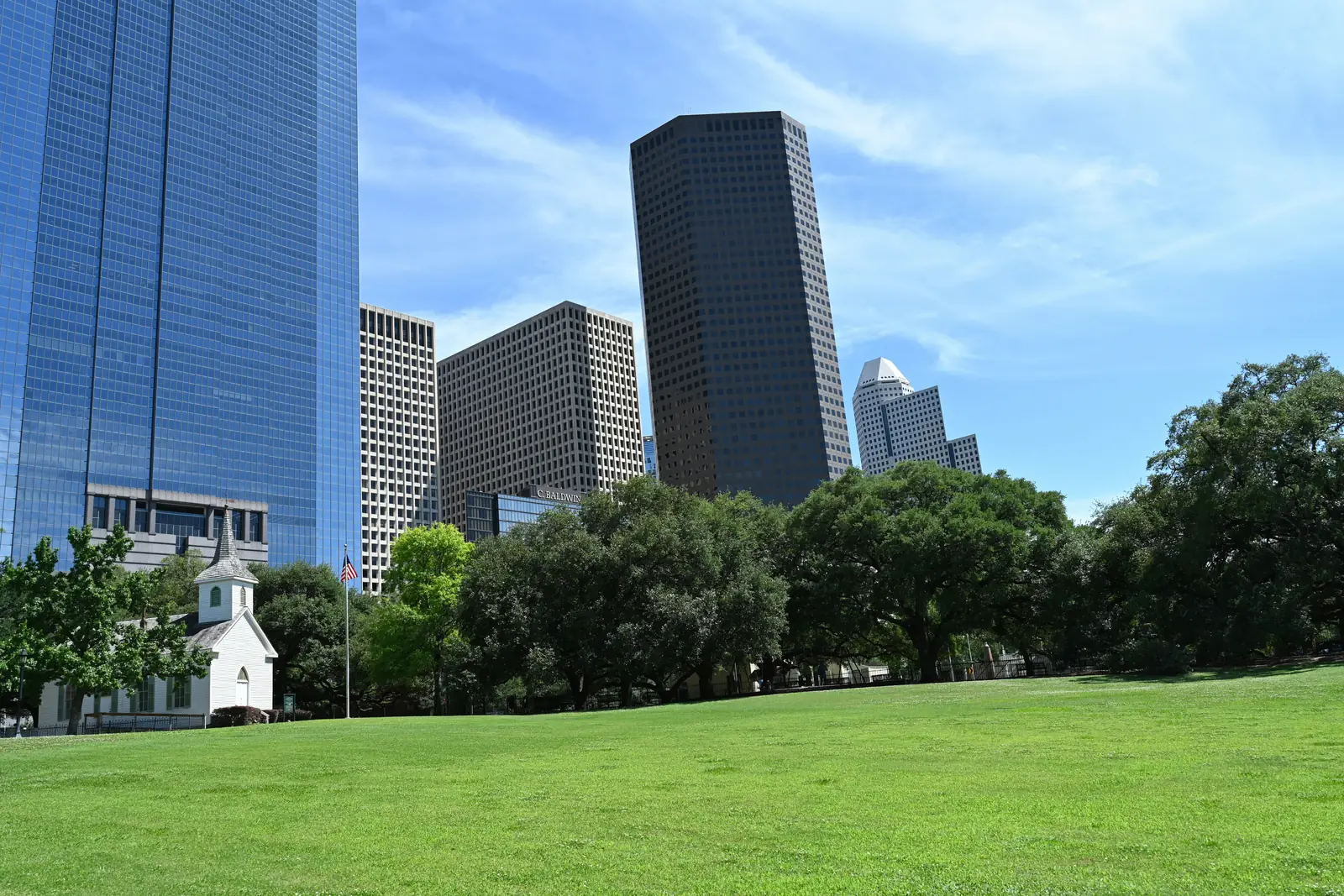 The Houston skyline rising behind a green park in the Museum District