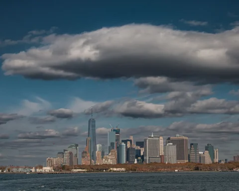 Lower Manhattan skyline seen across the harbor under dramatic clouds