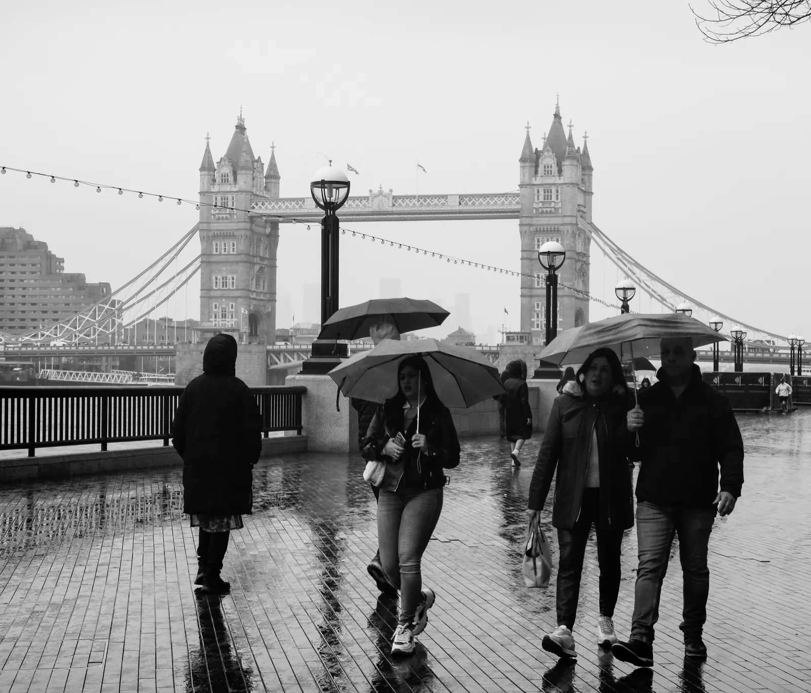Pedestrians walking in the rain near Tower Bridge in London