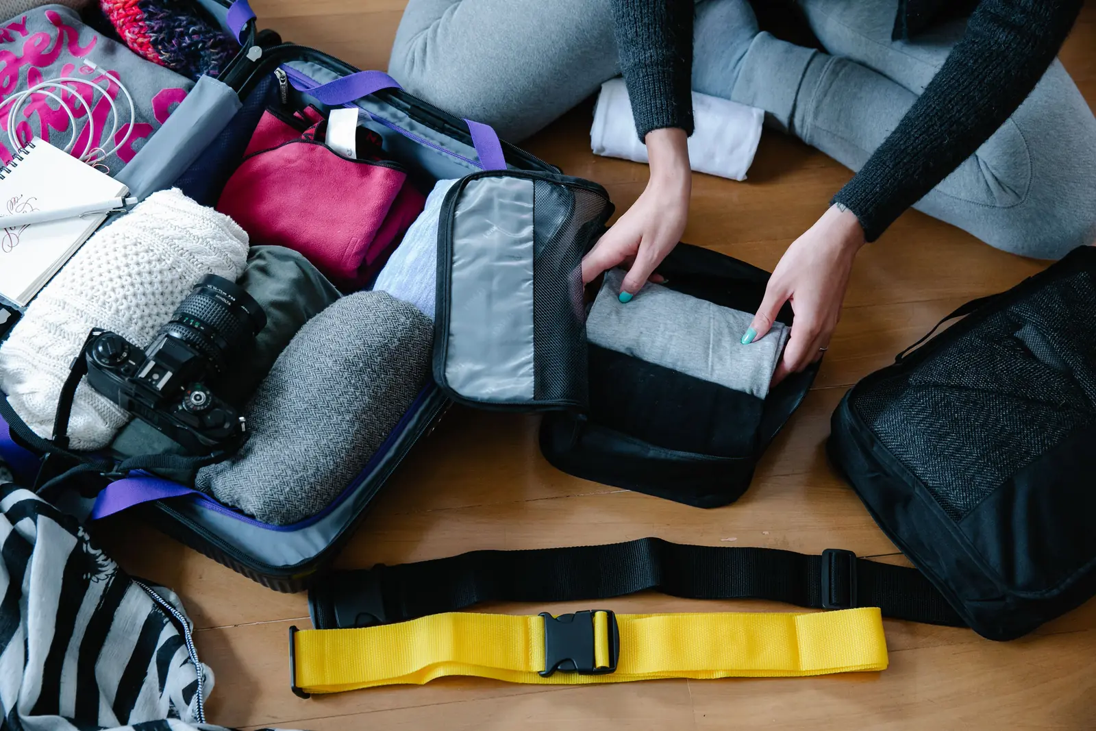 Zippered packing cubes laid out beside an open suitcase
