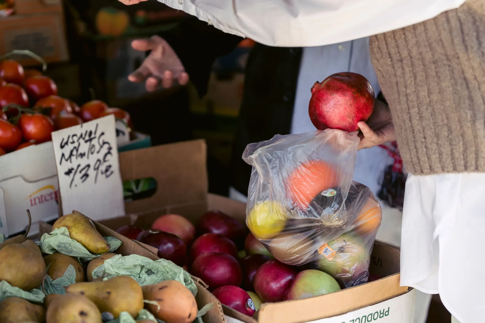 A shopper choosing fresh fruit at an open air market stall
