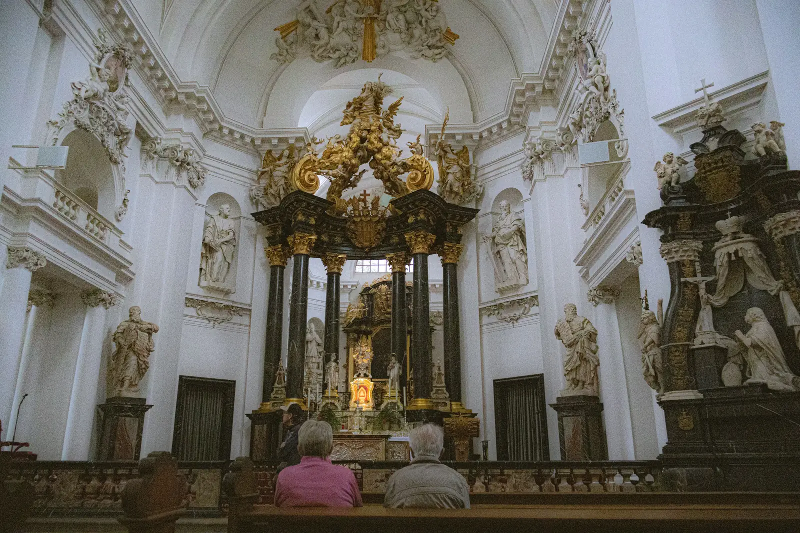 Visitors sitting inside the vaulted interior of Fulda Cathedral