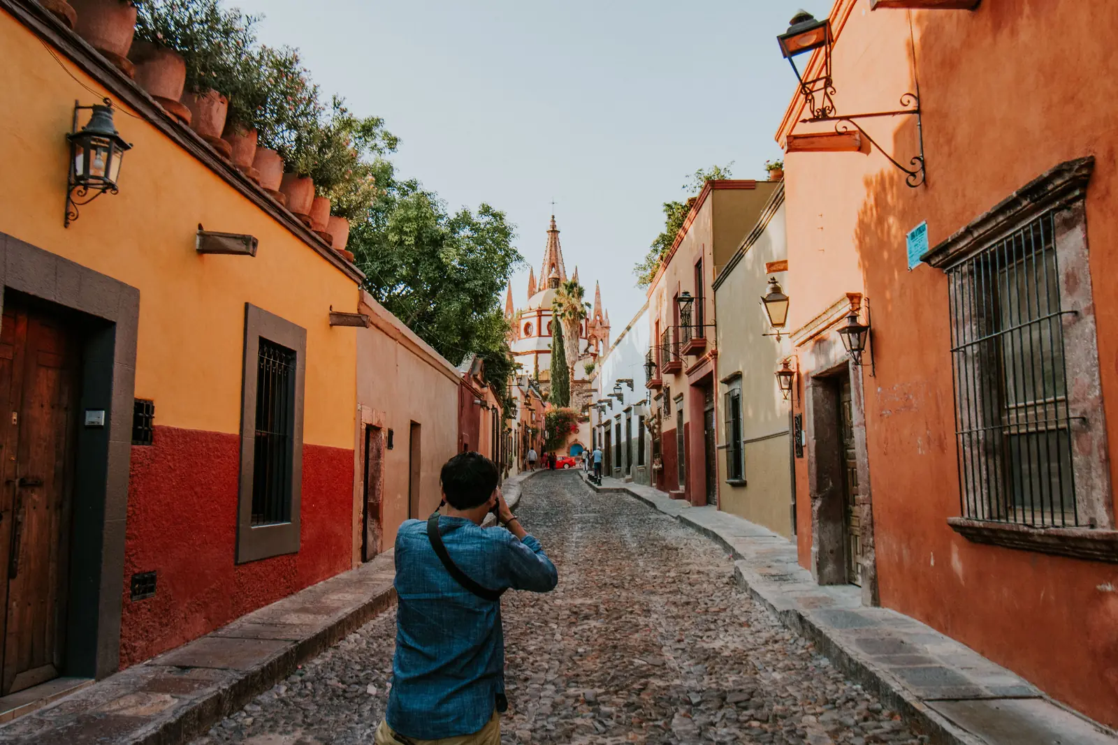 A visitor photographing a cobblestone street in San Miguel de Allende, Mexico
