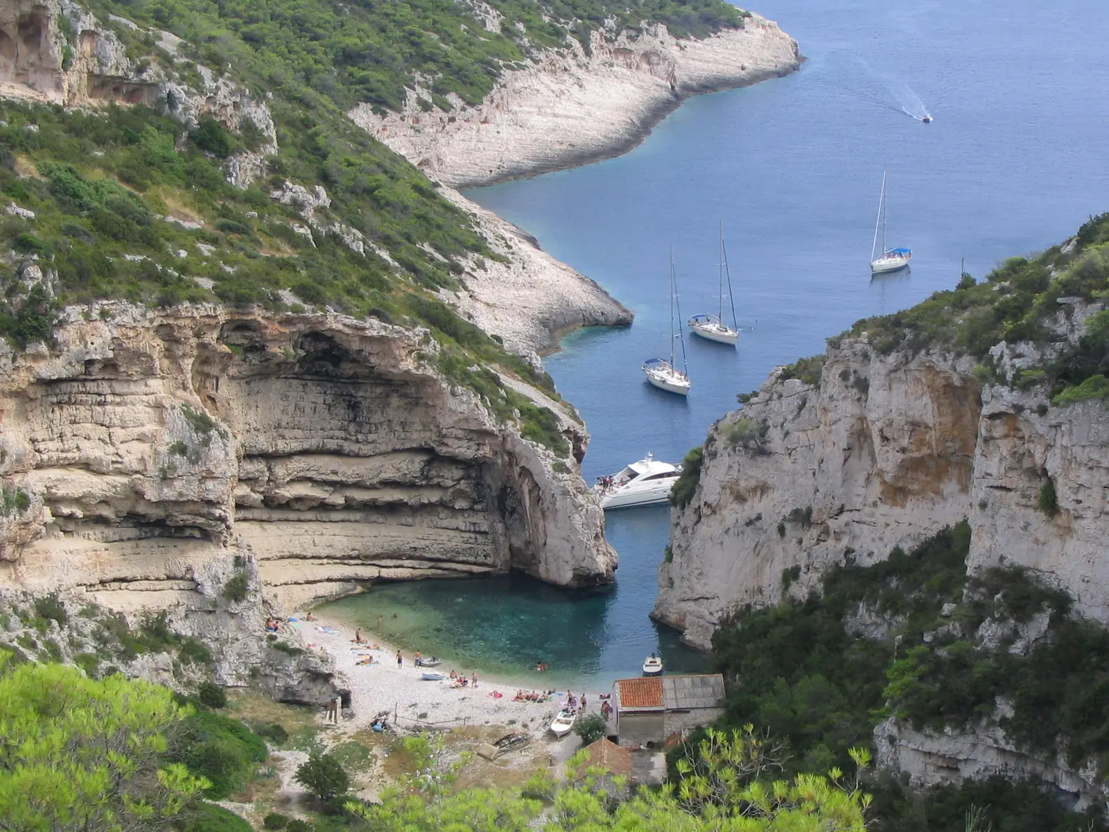 Stiniva beach framed by tall cliffs with boats anchored offshore on Vis, Croatia