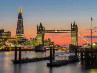 Tower Bridge lit up at sunset with the Shard behind it