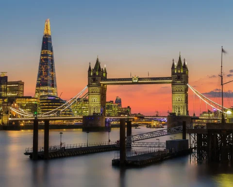 Tower Bridge lit up at sunset with the Shard behind it