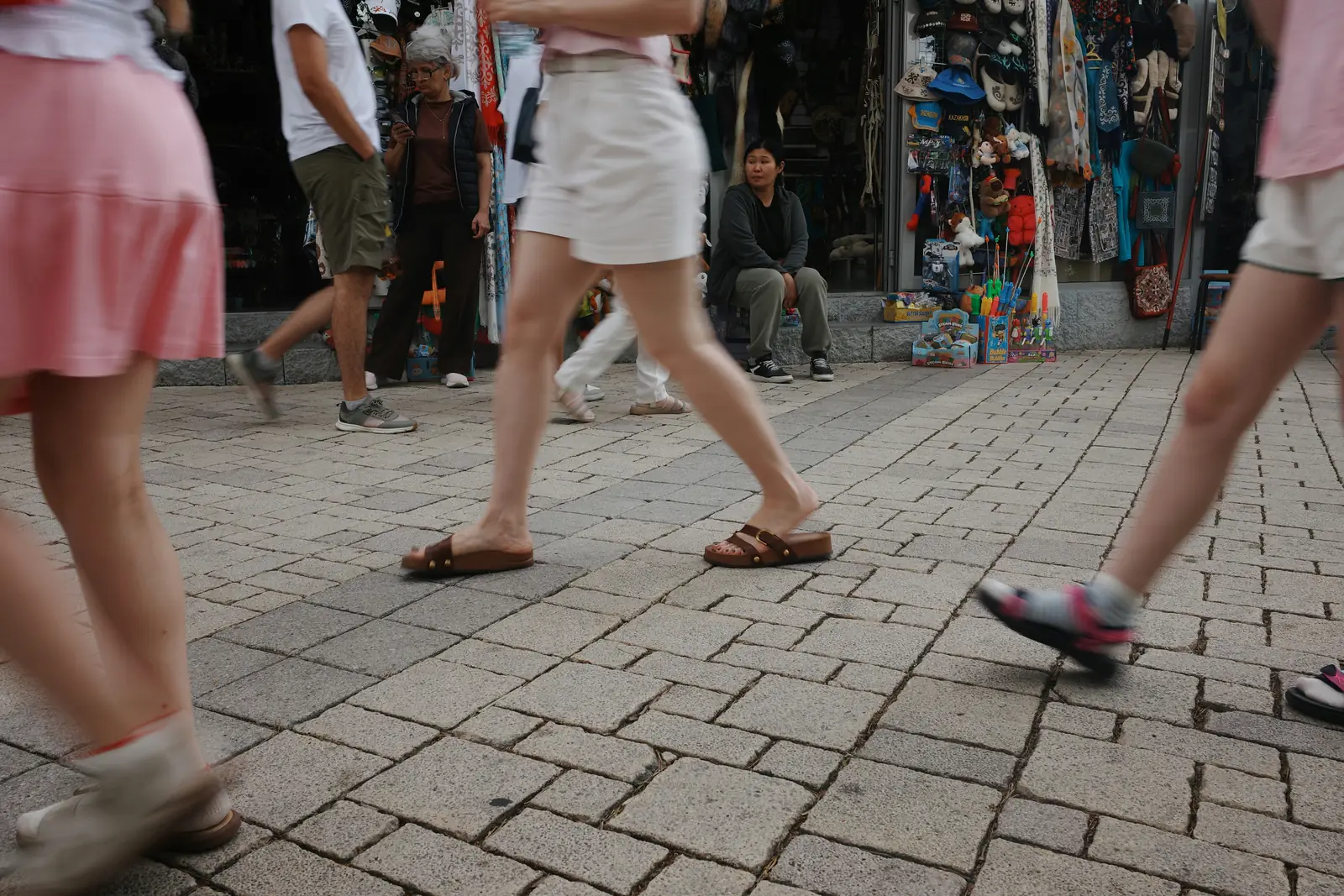 People walking a cobblestone street lined with shops in an old town
