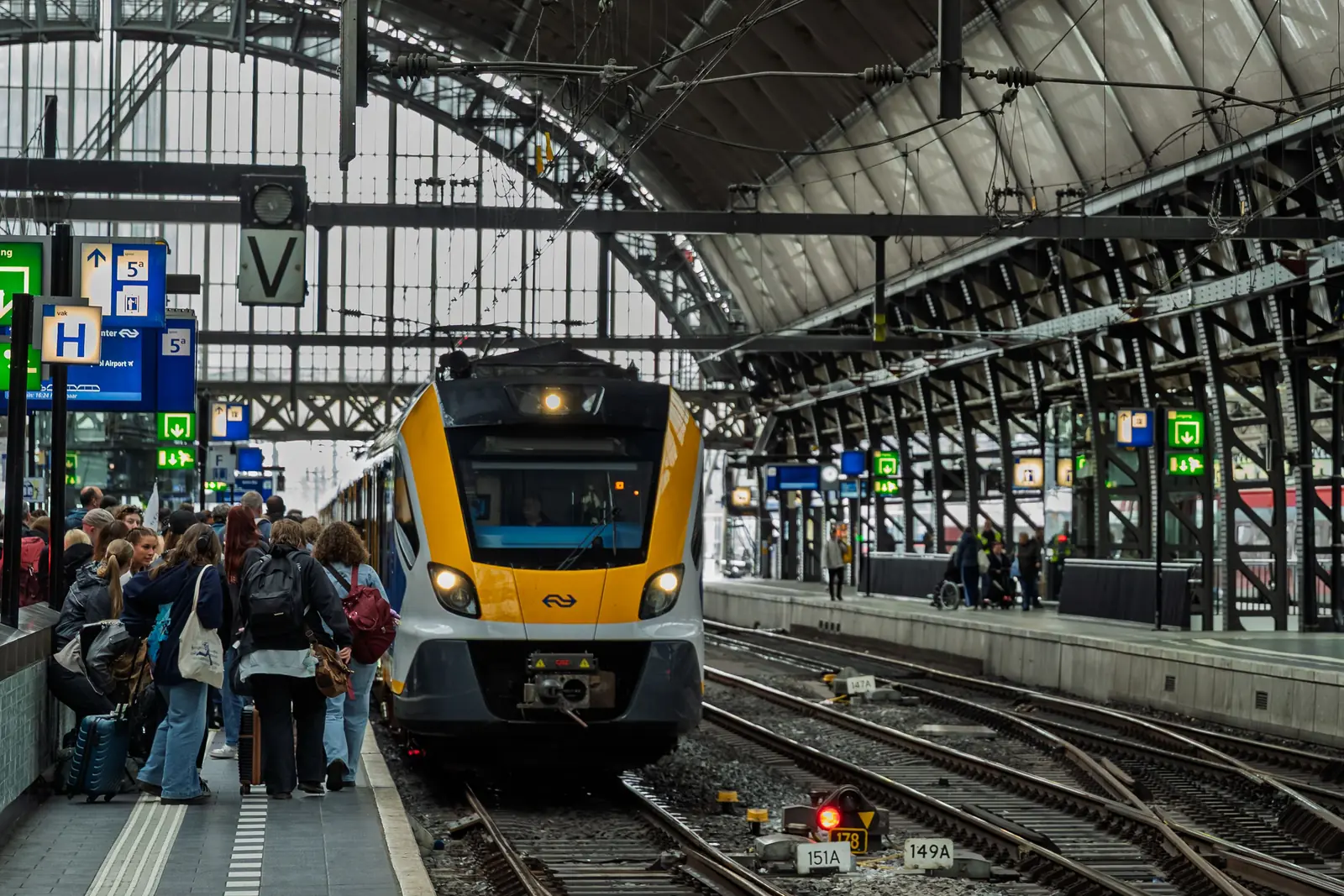 Travelers and trains along a busy European railway station platform