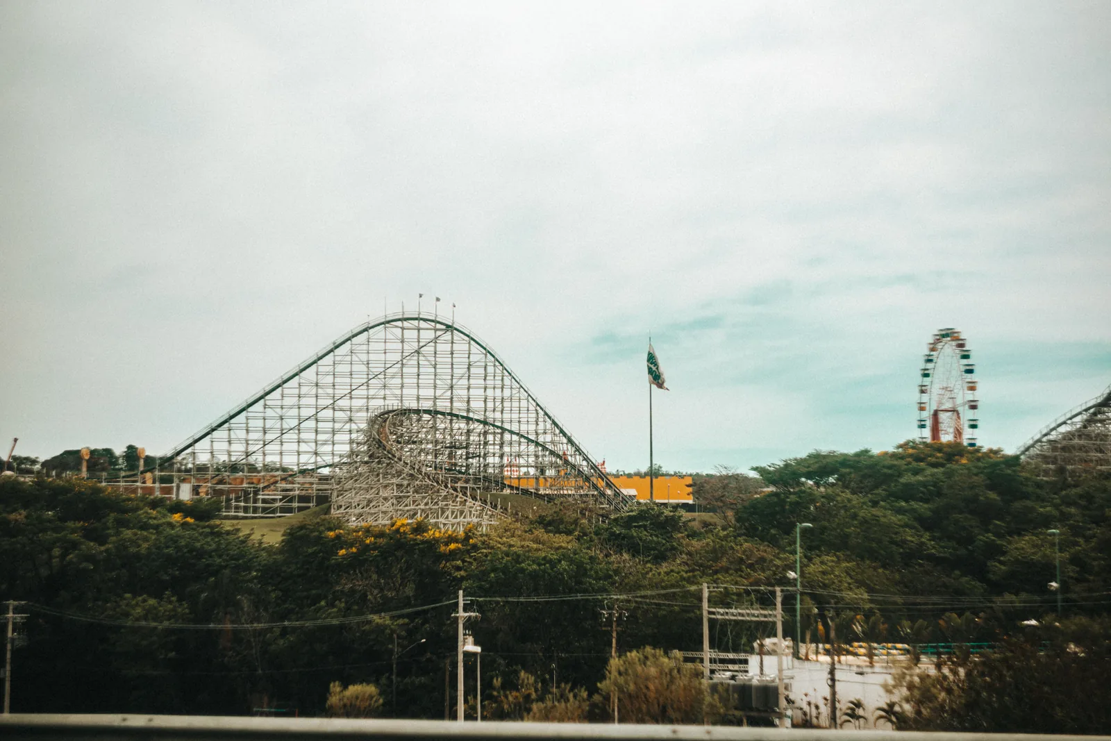 A wooden roller coaster and Ferris wheel at a seaside amusement park