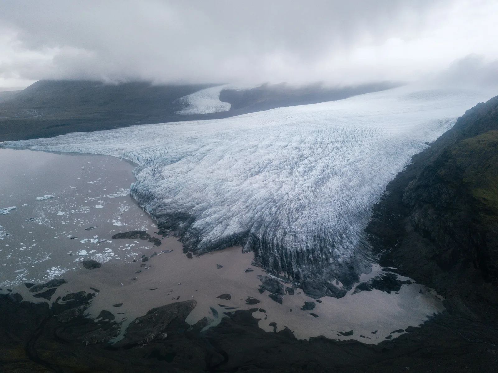 A glacier tongue spilling down toward the plain under a misty sky