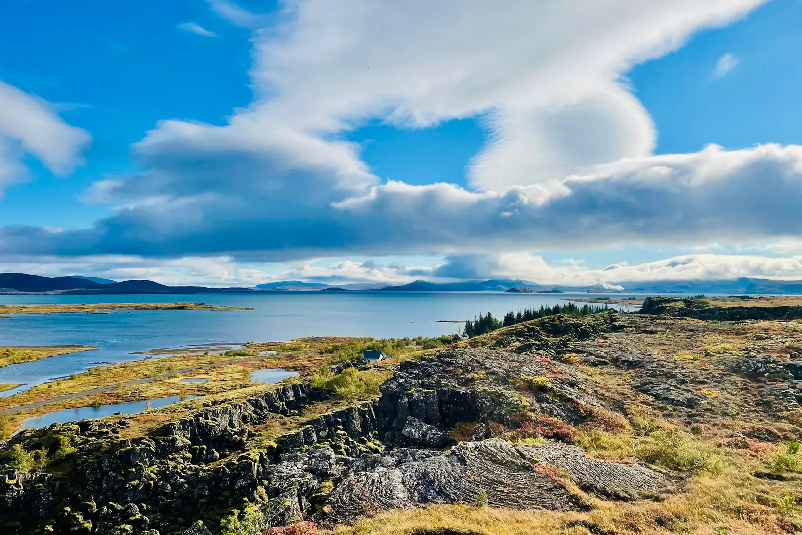 The lava plain and lake at Thingvellir National Park under a bright blue sky
