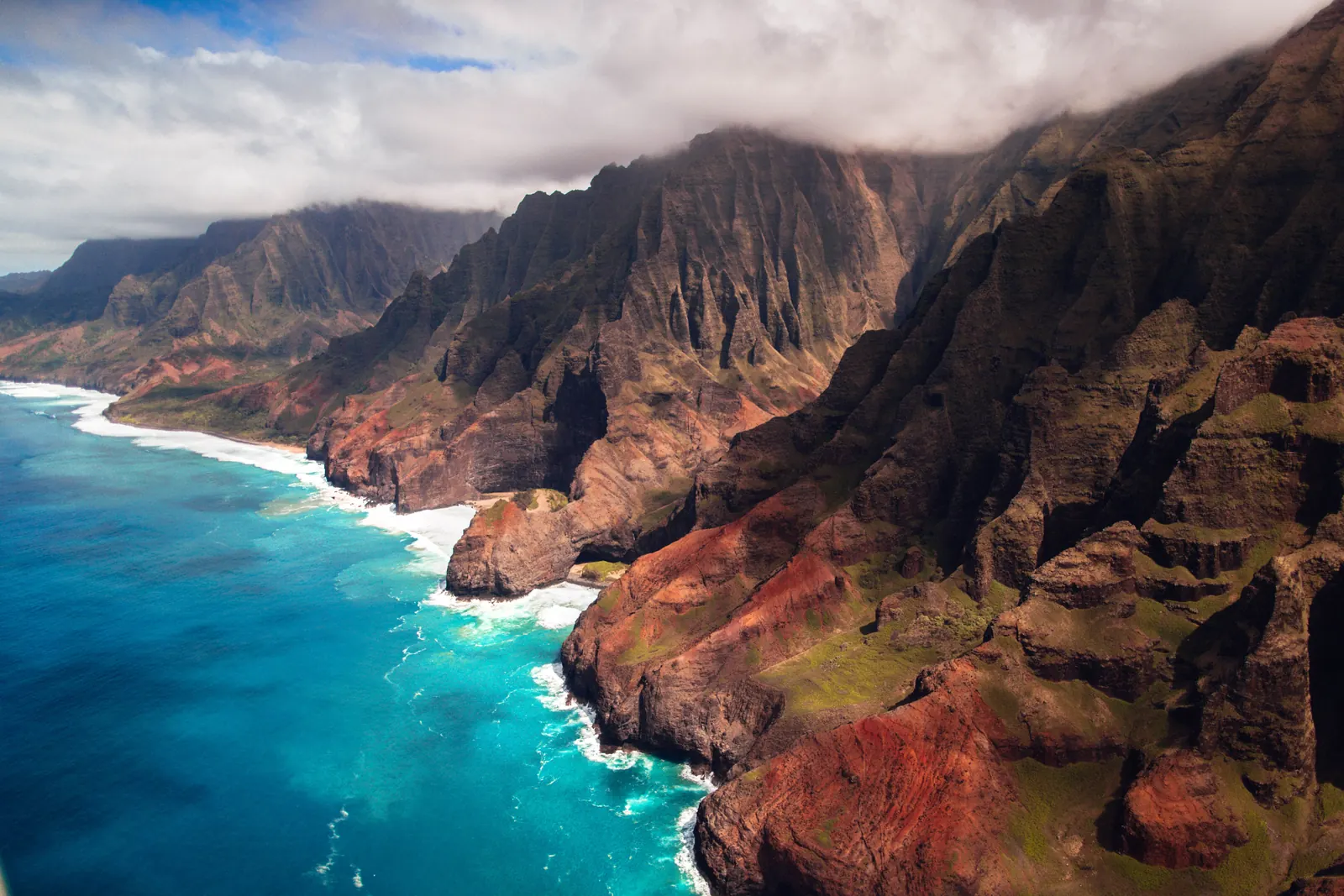 The fluted green cliffs of the Na Pali coast dropping into turquoise water on Kauai