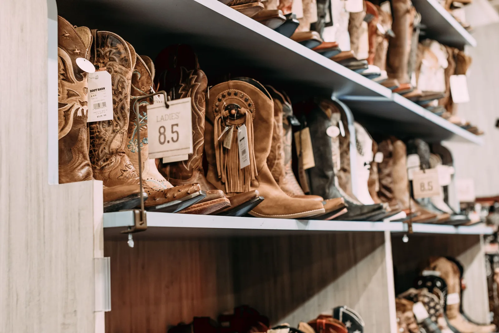 Rows of cowboy boots on shelves with size tags
