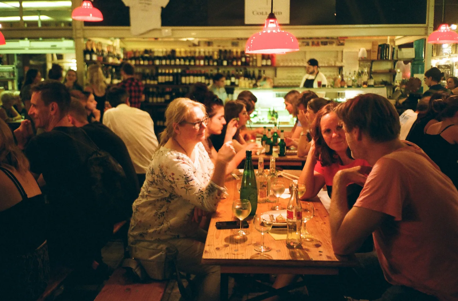 People sharing bottles of wine at a busy neighborhood wine bar