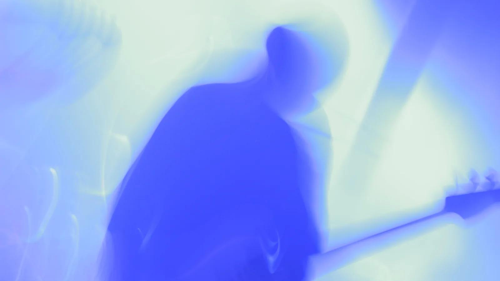 A guitarist playing on a small stage in a dark club