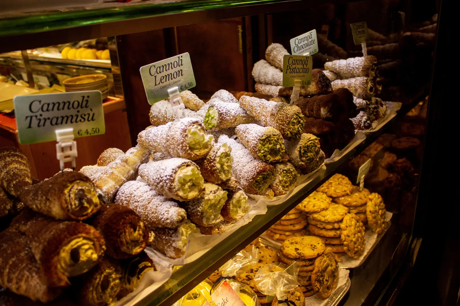 A bakery case packed with fresh cannoli and Italian pastries