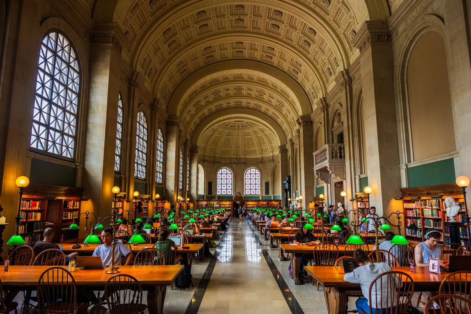 Green lamps along the long tables under the barrel vaulted ceiling of Bates Hall at the Boston Public Library