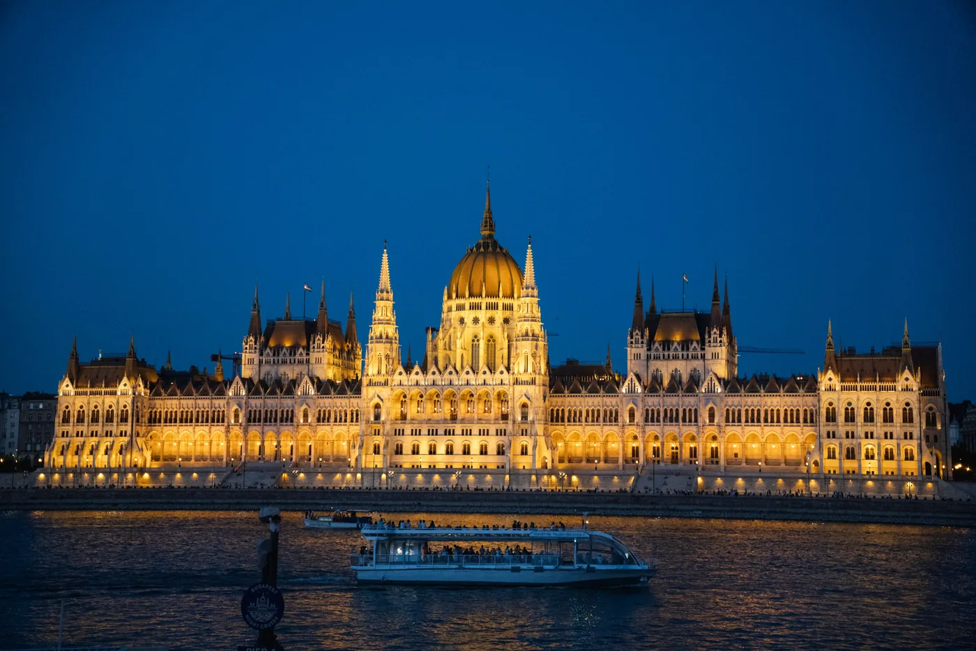 A cruise boat passing the lit Hungarian Parliament building on the Danube at night