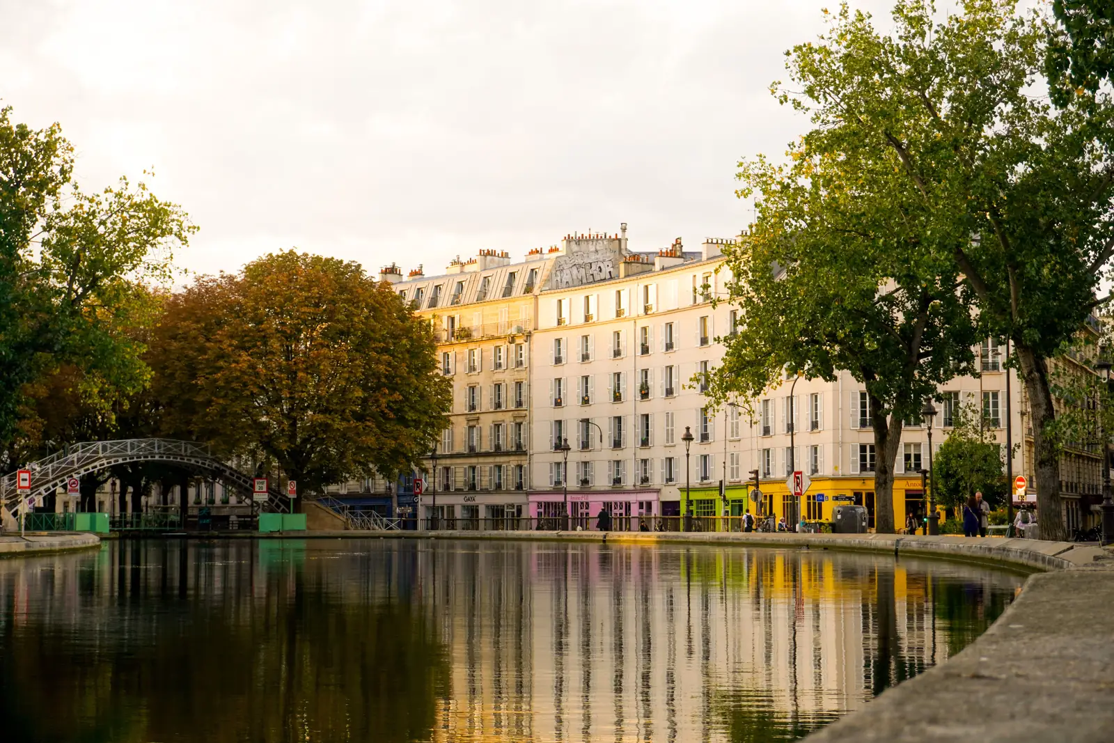 Trees and footbridges reflected in the water of Canal Saint Martin in Paris