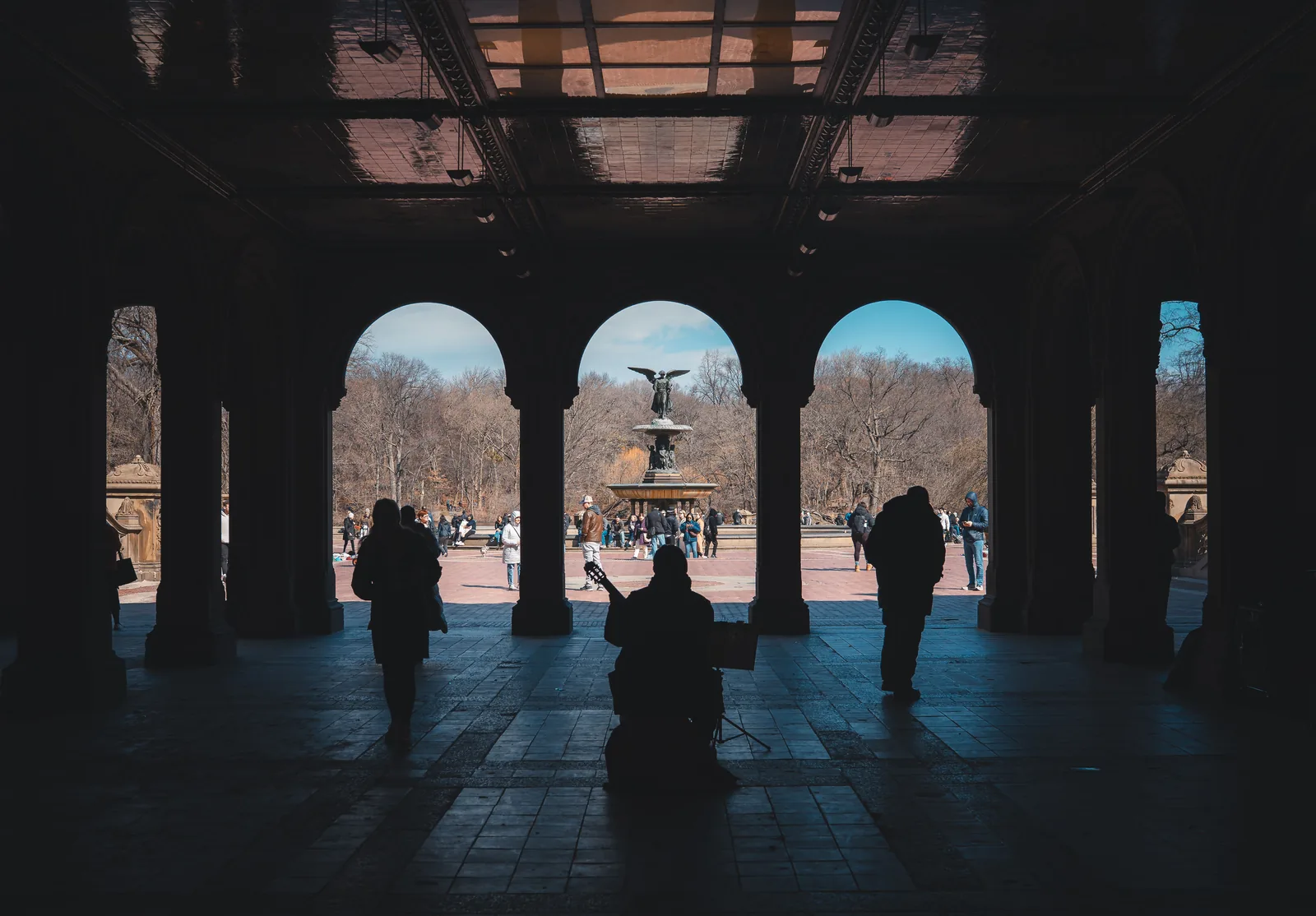 Figures silhouetted under the arches at Bethesda Terrace in Central Park