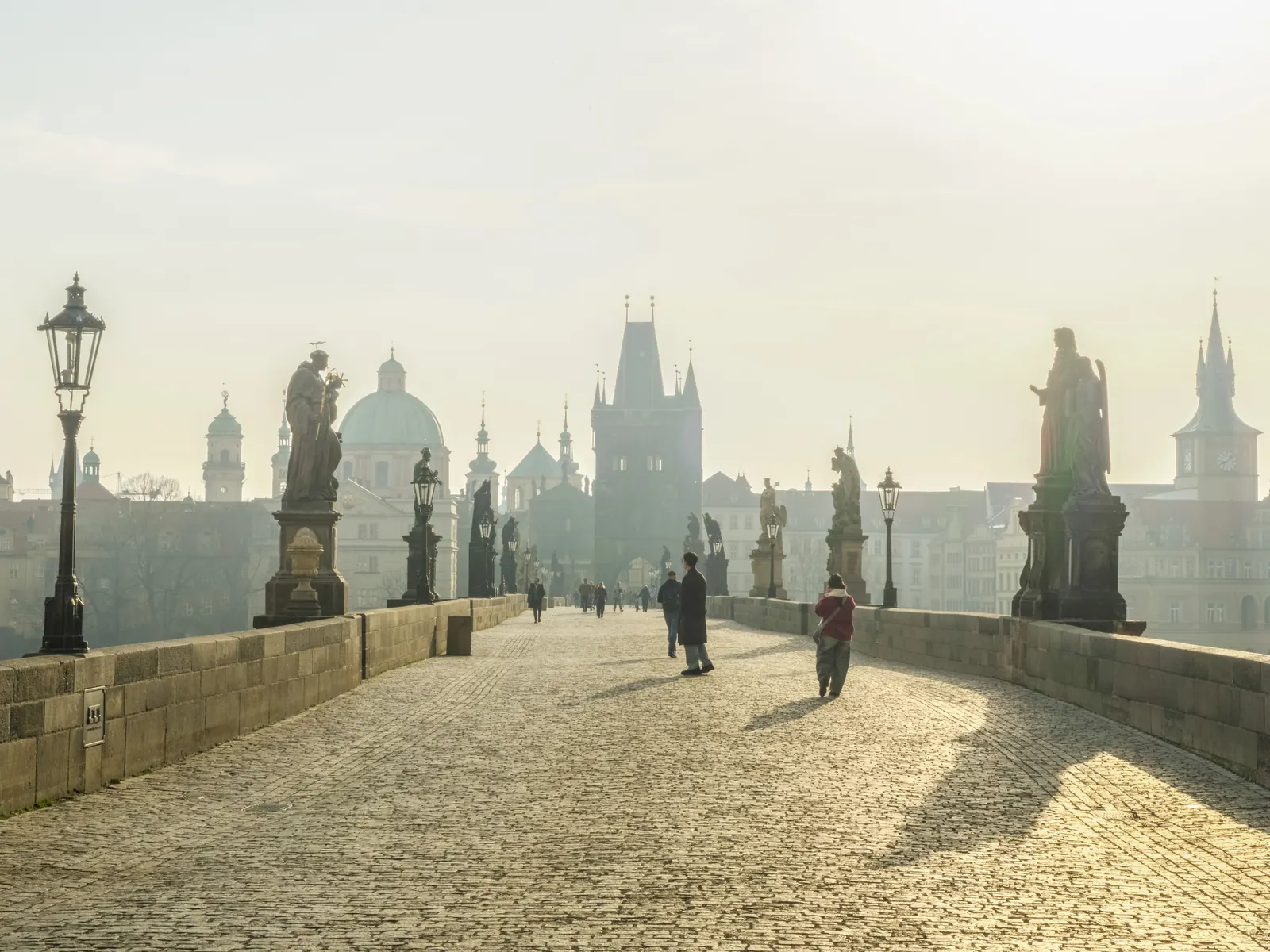 Charles Bridge in Prague at sunrise with mist over the statues