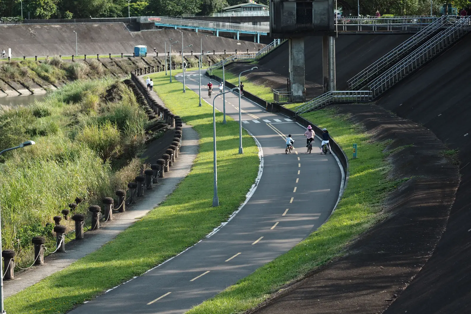 Cyclists riding a paved bike lane along a riverbank