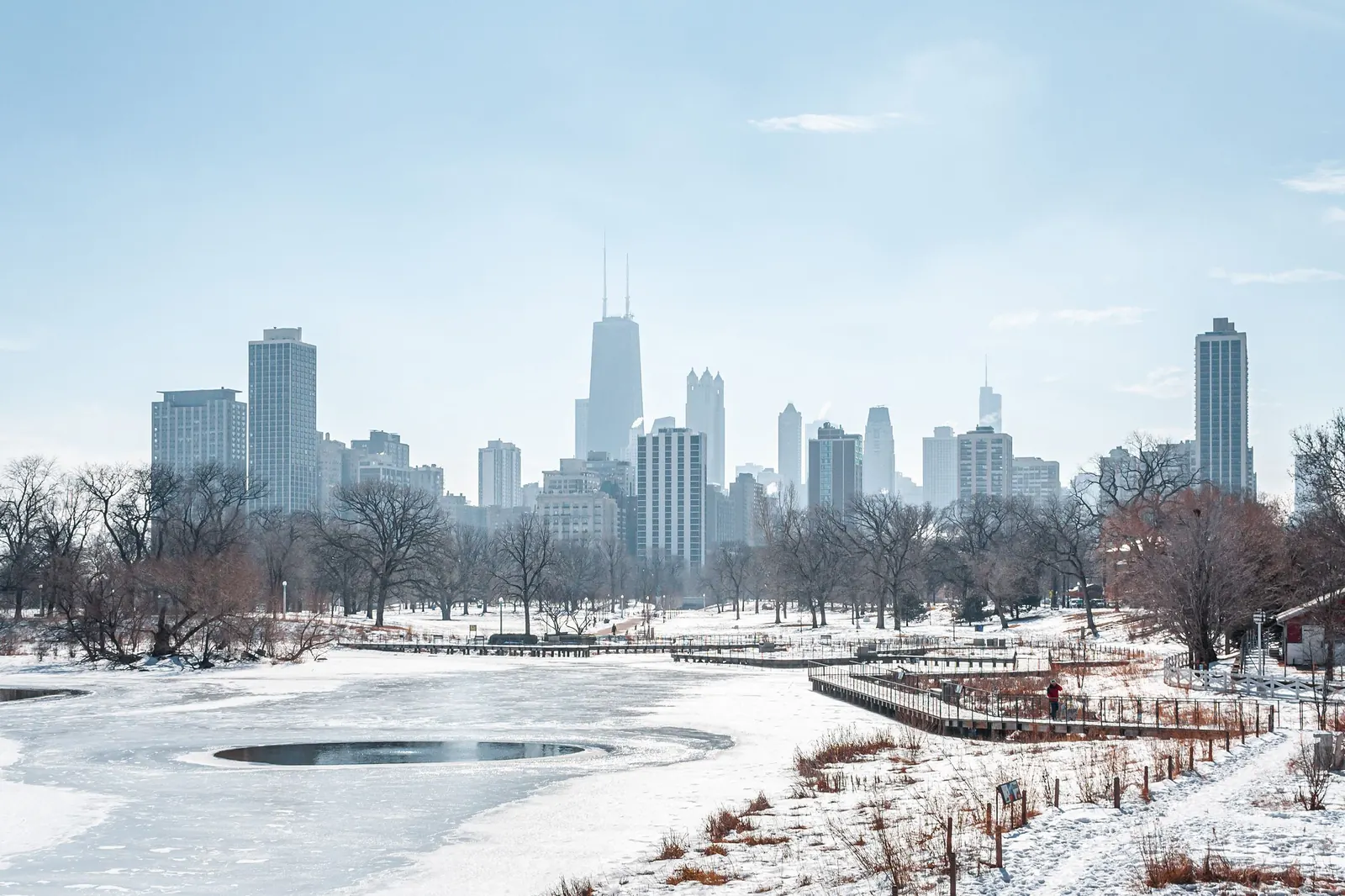 The Chicago skyline seen across a frozen lagoon and bare trees in Lincoln Park