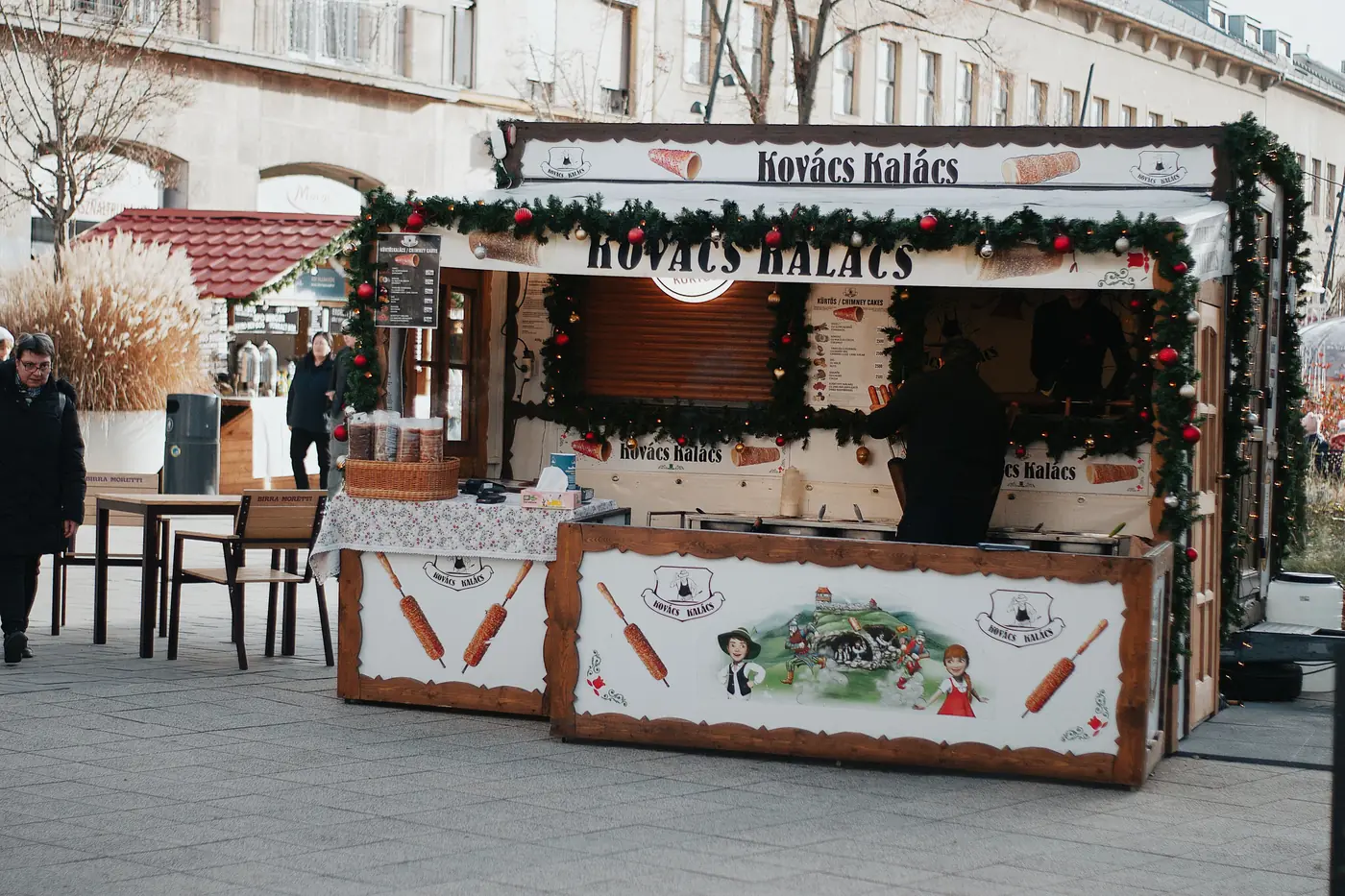 A Hungarian chimney cake stall decorated with garland at a Christmas market