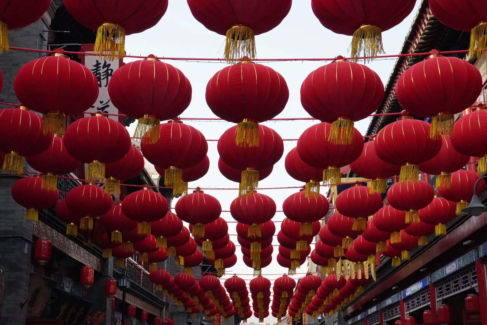 Rows of red paper lanterns strung above a Chinatown street