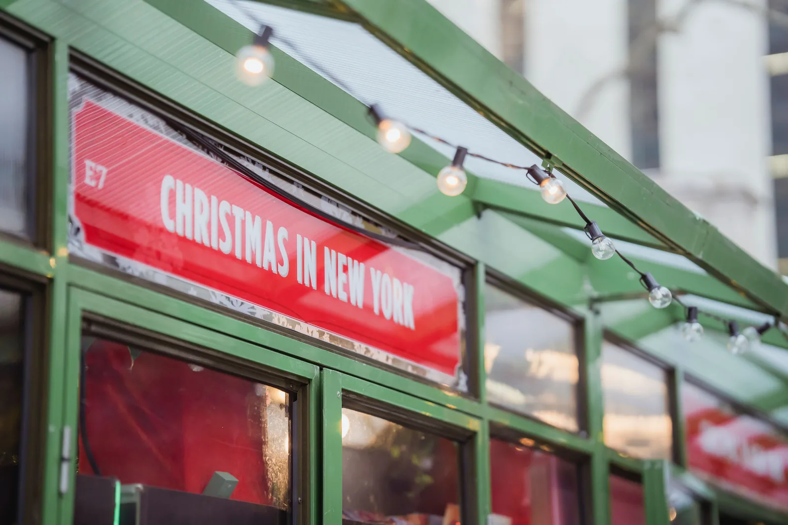 A Christmas in New York sign and string lights on a storefront