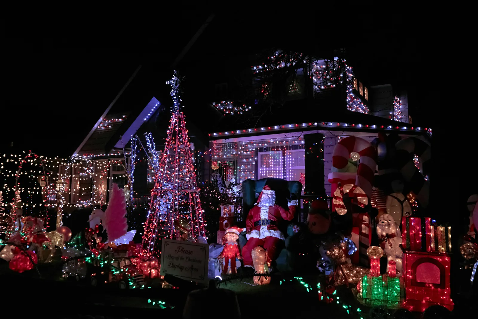 A house covered end to end in Christmas lights and lit figures at night