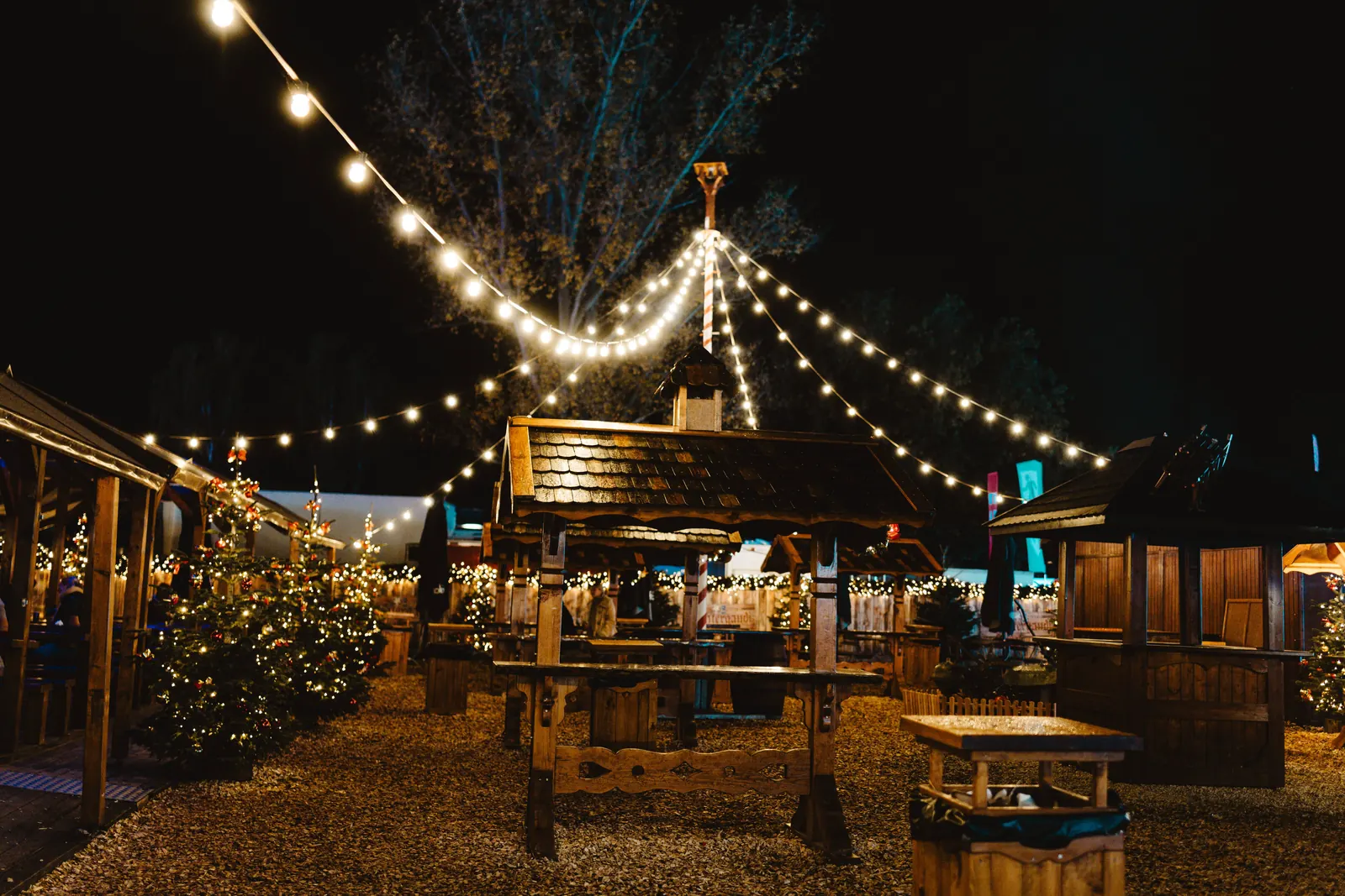 Wooden market stalls lit with string lights at night