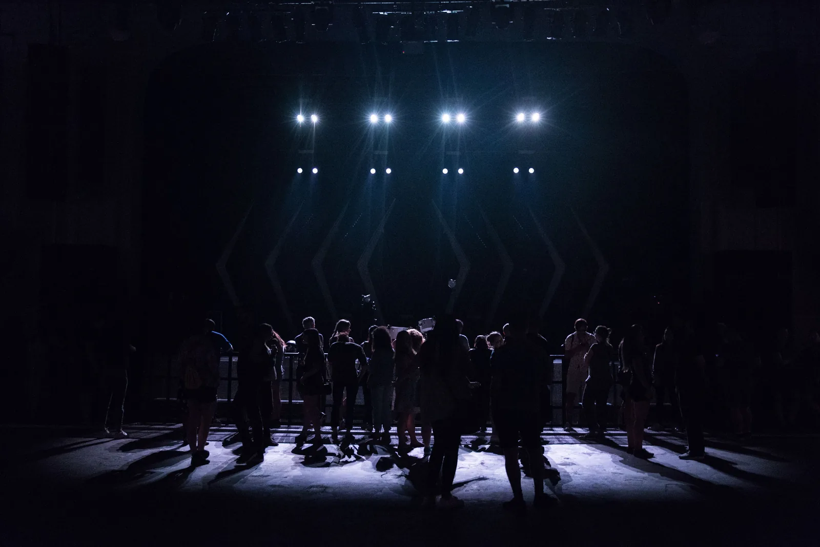 Silhouettes of an audience watching a lit stage
