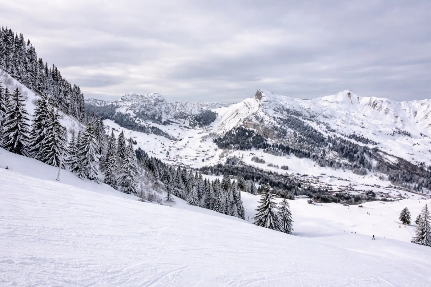 A groomed piste and snow covered peaks in the French Alps