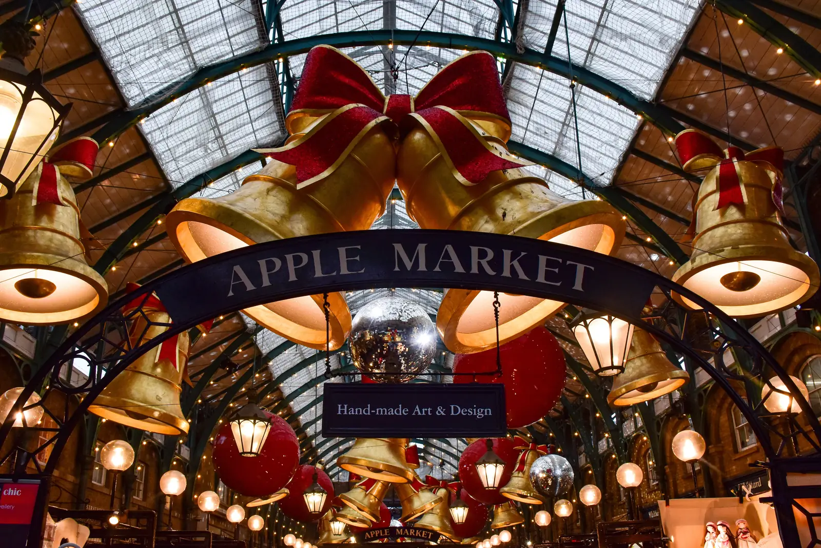Giant gold bells and red baubles hanging over the Apple Market in Covent Garden